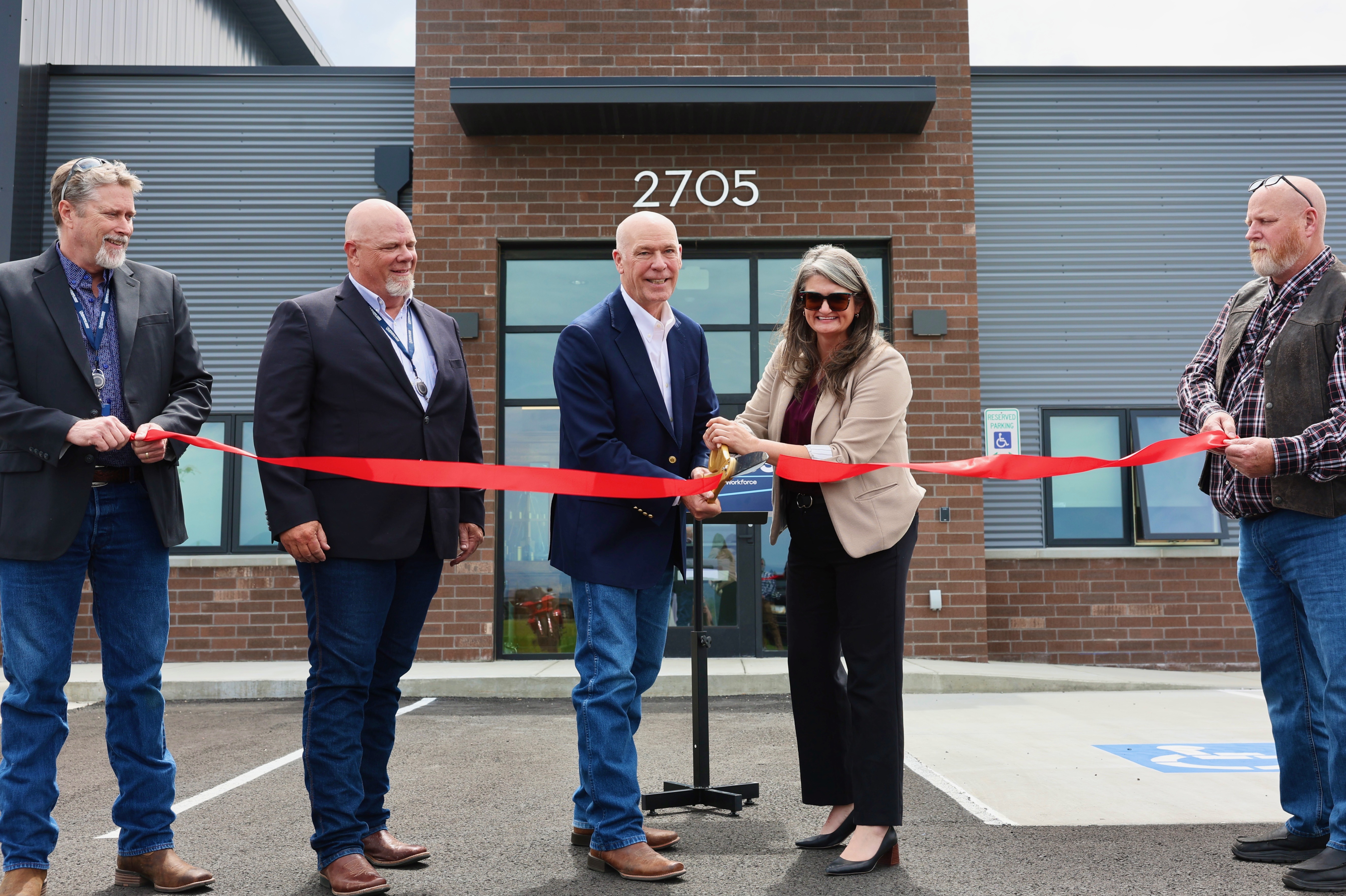 Gov. Gianforte (center left) and DLI Commissioner Sarah Swanson (center right) cutting the ribbon on a new state-owned facility in Helena