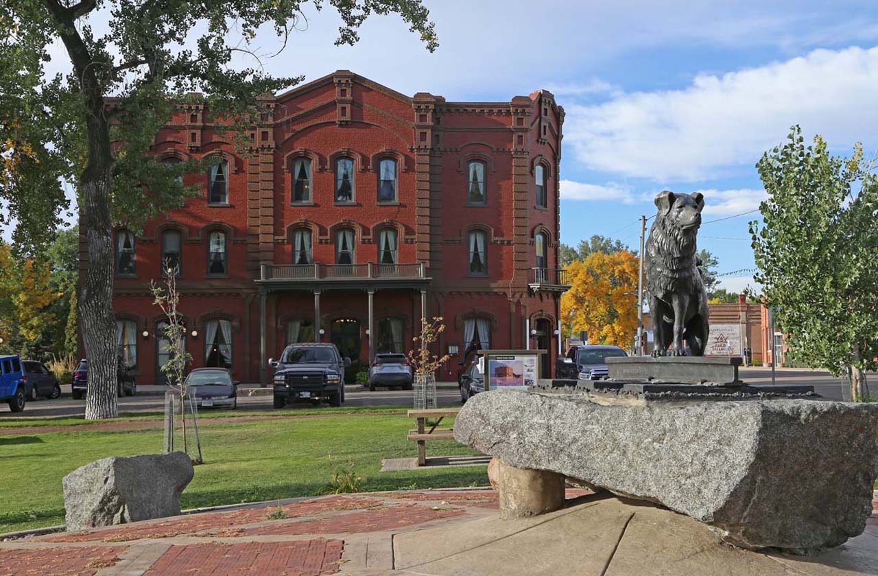 A statue of a dog and an old hotel building in Fort Benton, MT.